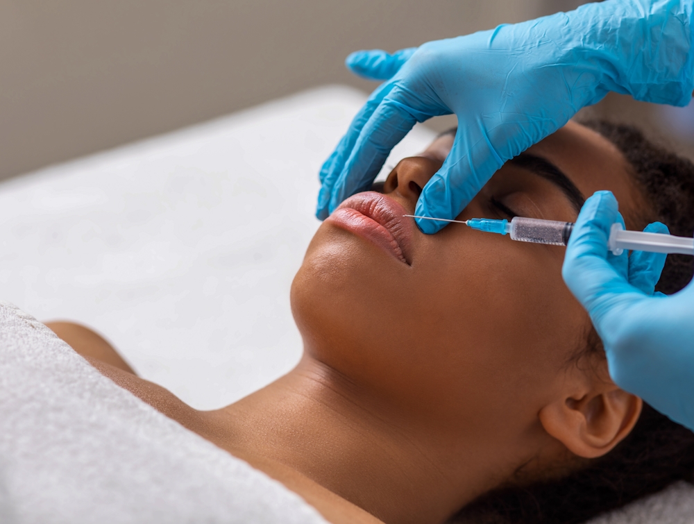 Black lady getting lip filling injection at modern beauty salon, closeup, copy space